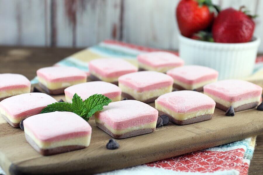 Neapolitan keto fat bombs in small squares on a cutting board
