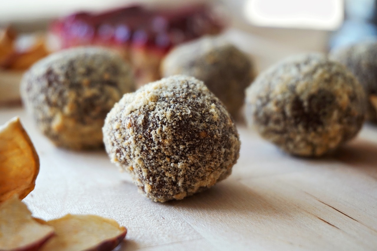 keto fat bombs balls on a wooden countertop next to dried apples