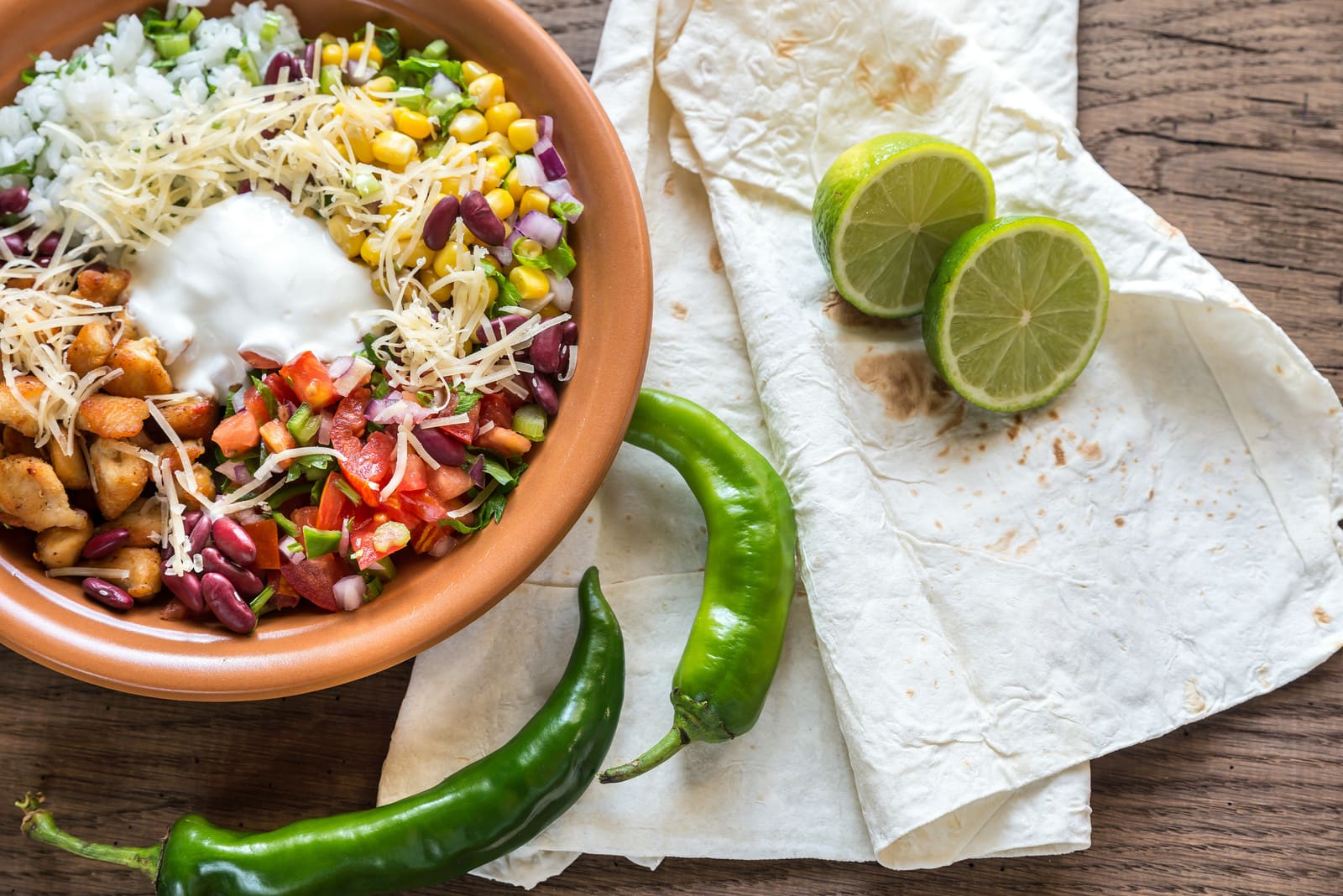 keto chipotle bowl with sour cream on top next to napkins with lime halves