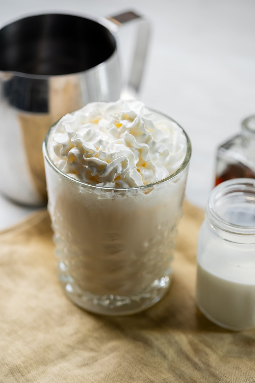 keto crack coffee keto coffee in a glass with whipped cream on top next to a pitcher