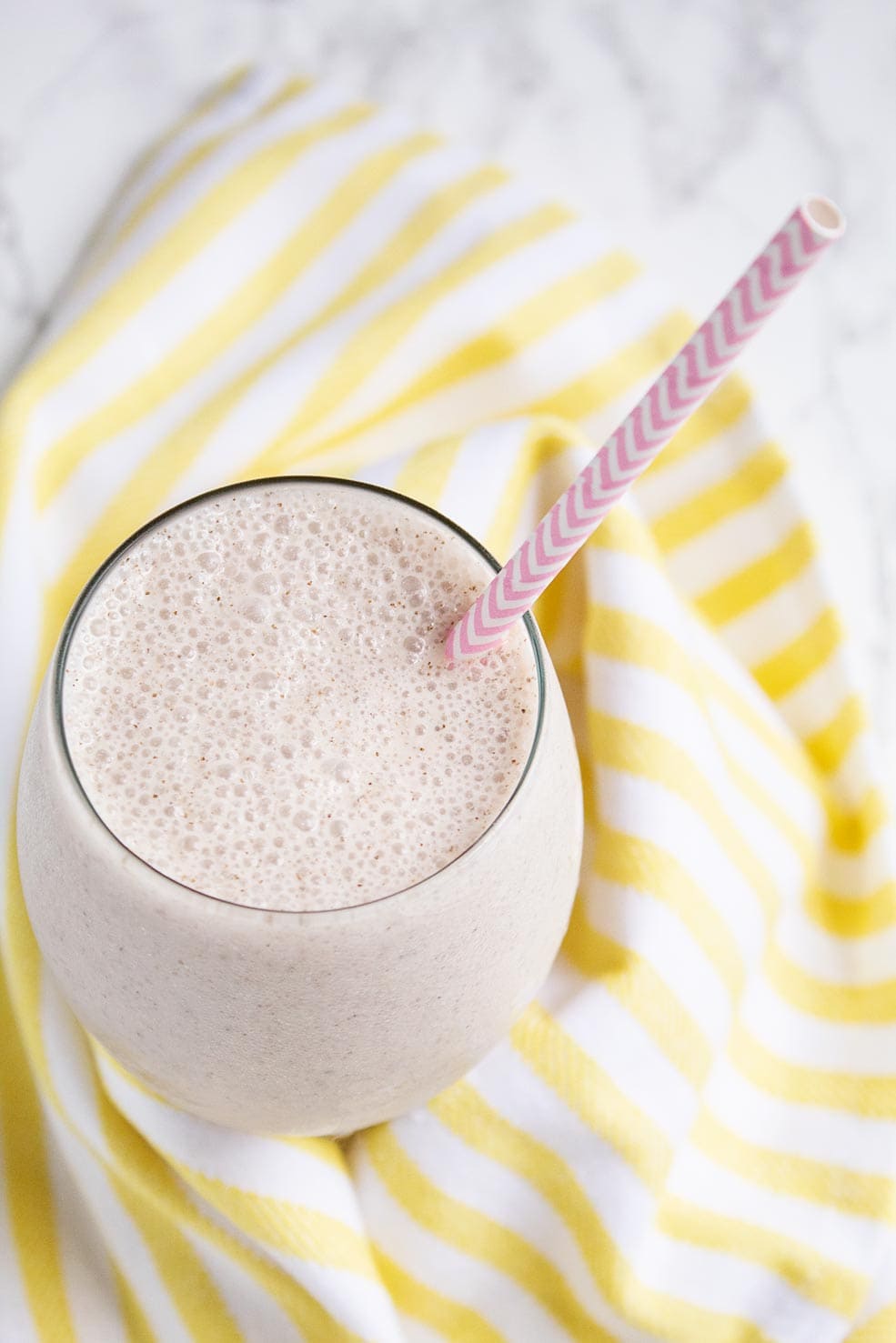 keto ice cream coffee smoothie in a cup with a pink straw over a yellow striped towel