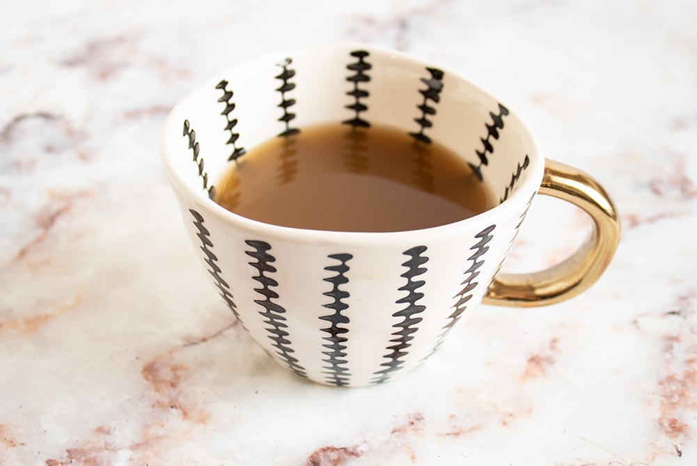 closeup of keto bone broth in cup with gold handle