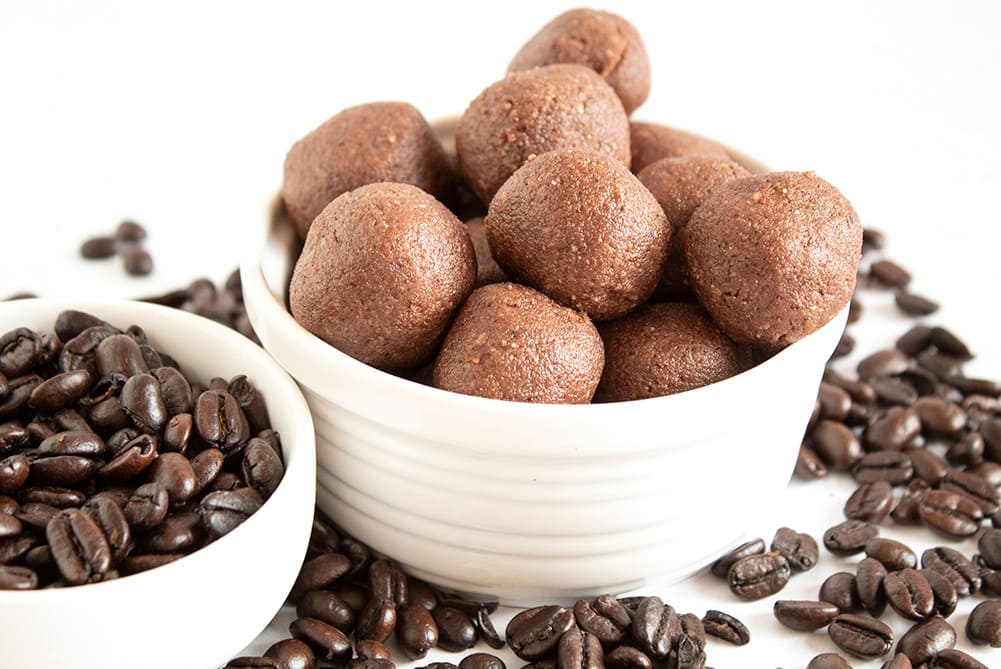 keto chocolate coffee fat bombs in a white dish next to dish of coffee beans