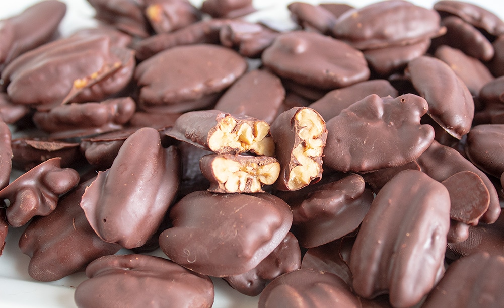 closeup of chocolate covered pecans with several broken in half