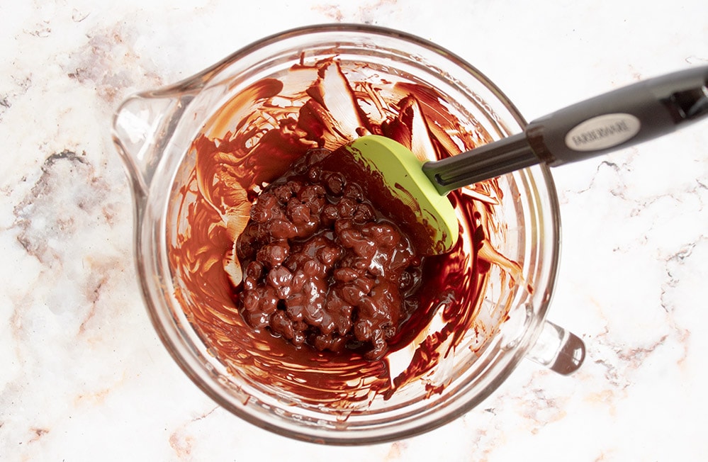 bowl with chocolate covered pecans with a spatula sticking out