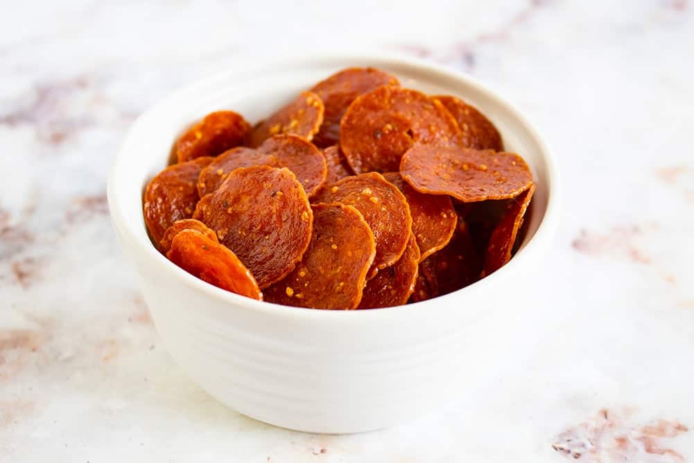 keto pepperoni chips in a white bowl on a countertop