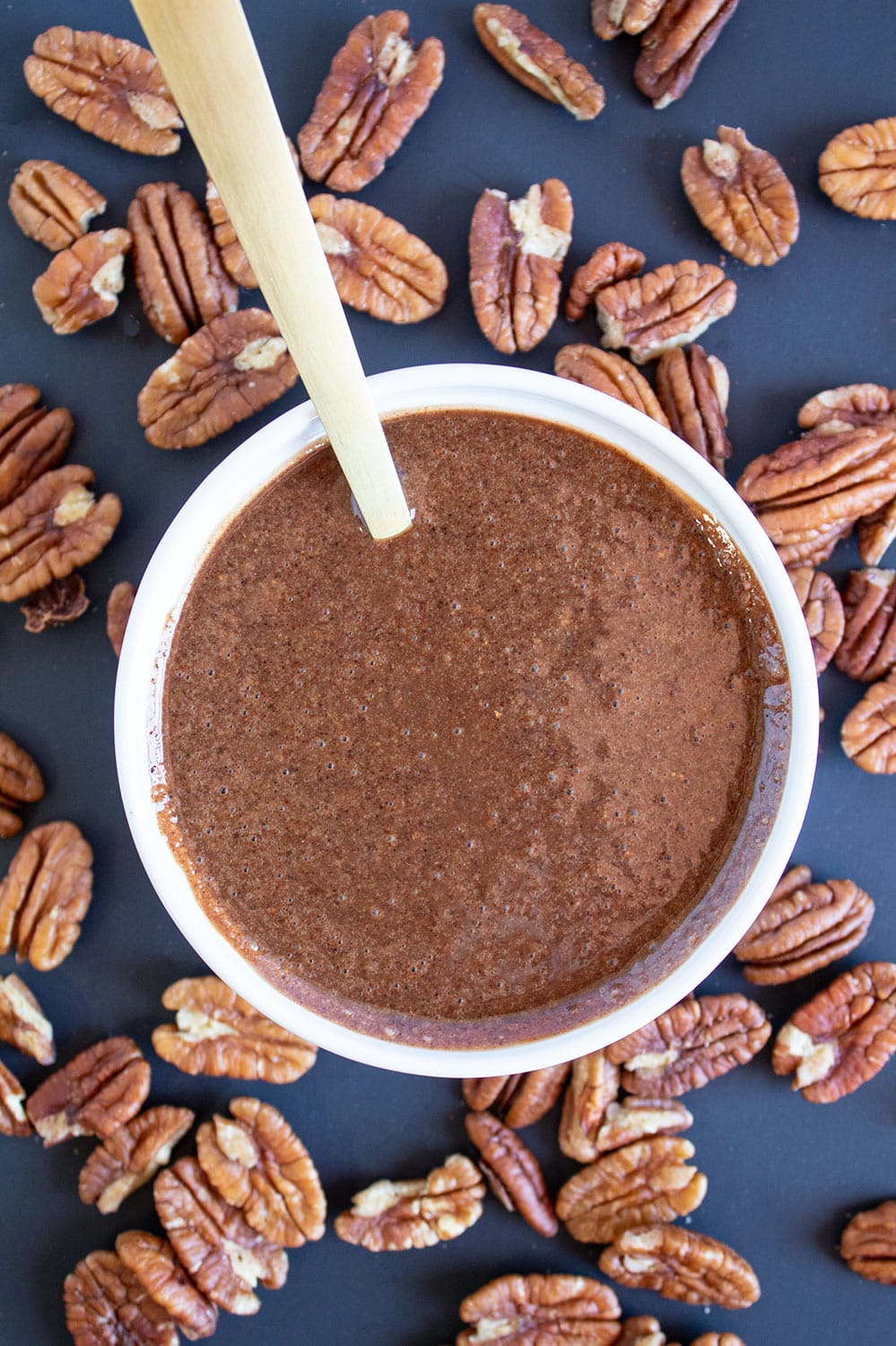 chocolate coffee pecan butter in a white bowl with a gold spoon sticking out