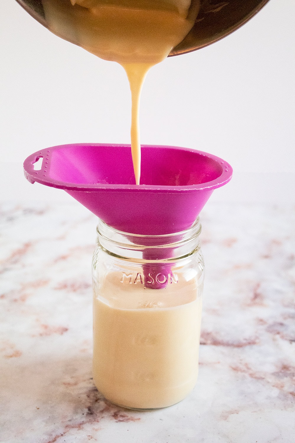 keto condensed milk being poured from a bowl into a mason jar