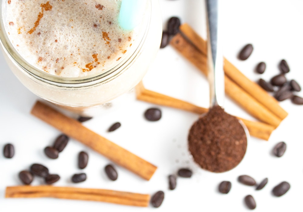 closeup of keto iced coffee top with cinnamon sticks and coffee grounds in background