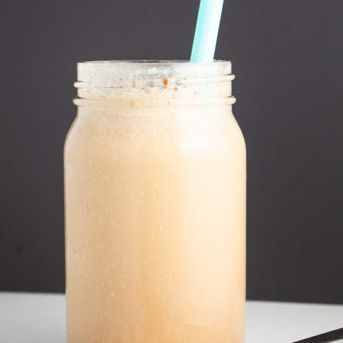 vanilla cinnamon keto iced coffee in front of a black background by coffee beans