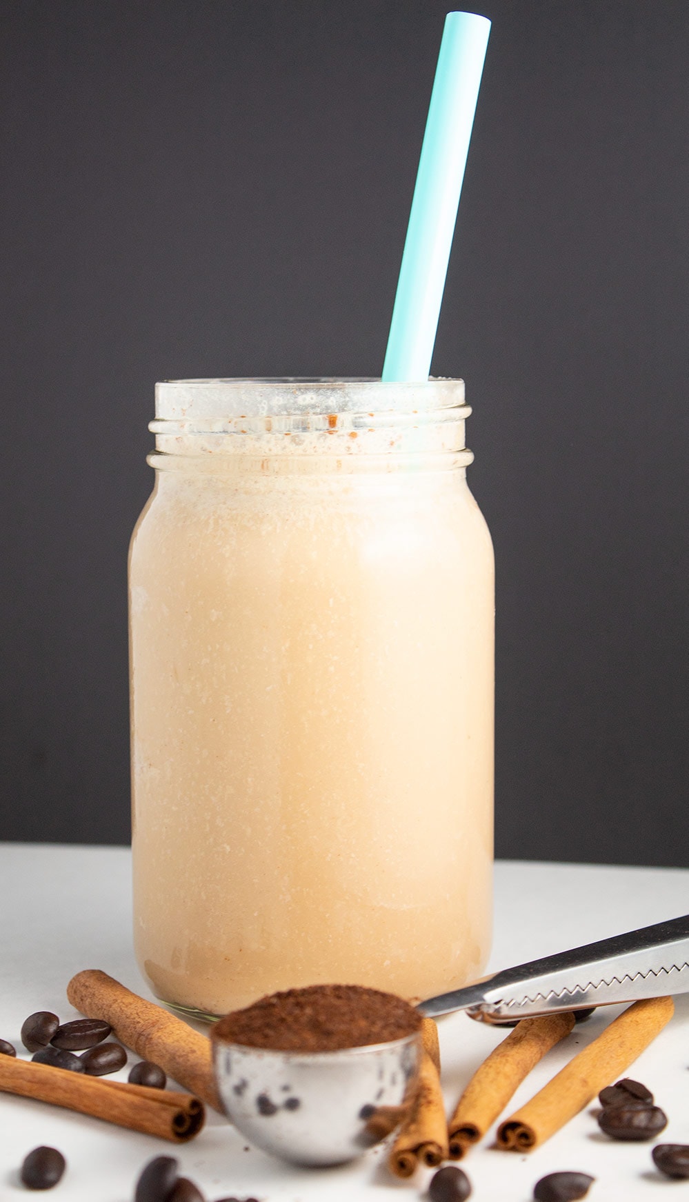 vanilla cinnamon iced coffee in front of a black background by coffee beans