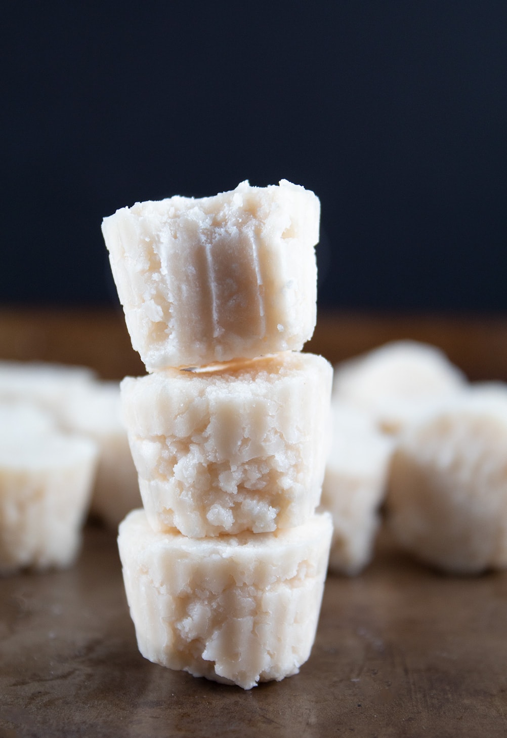 three maple coconut fat bombs stacked to show keto fat bomb recipe in front of black background
