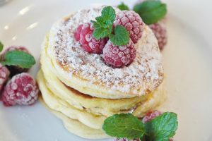 keto brekafast pancakes stacked with frozen raspberries on top
