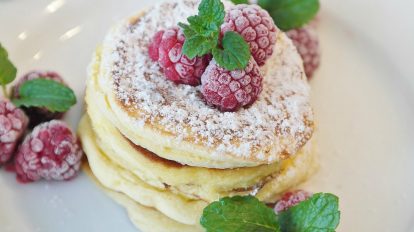 keto brekafast pancakes stacked with frozen raspberries on top