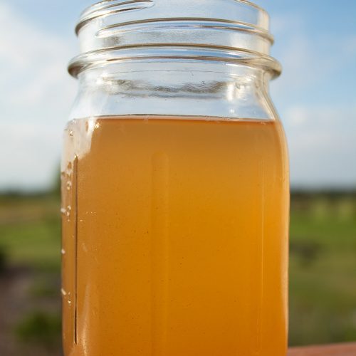 keto detox drink in a ball canning jar sitting on a ledge in front of scenery