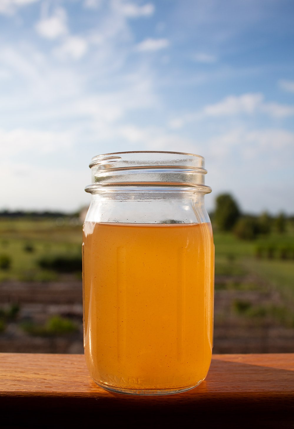 keto detox water sitting on a ledge with beautiful blue skies and green grass behind it