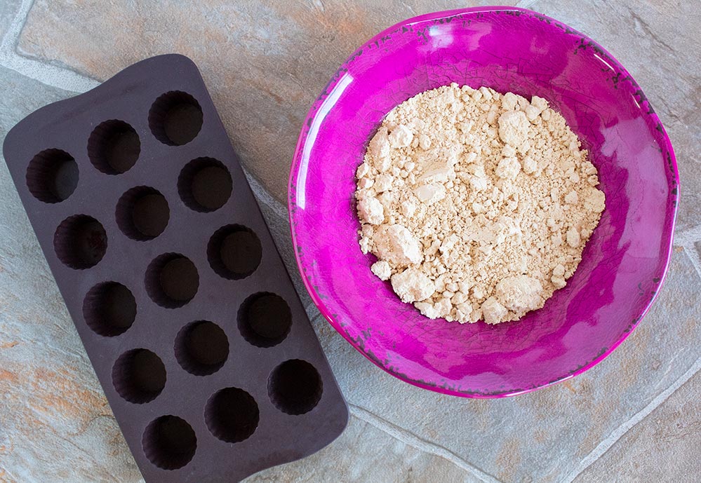 keto peanut butter fat bombs ingredients including fat bombs mold and peanut butter powder in pink bowl