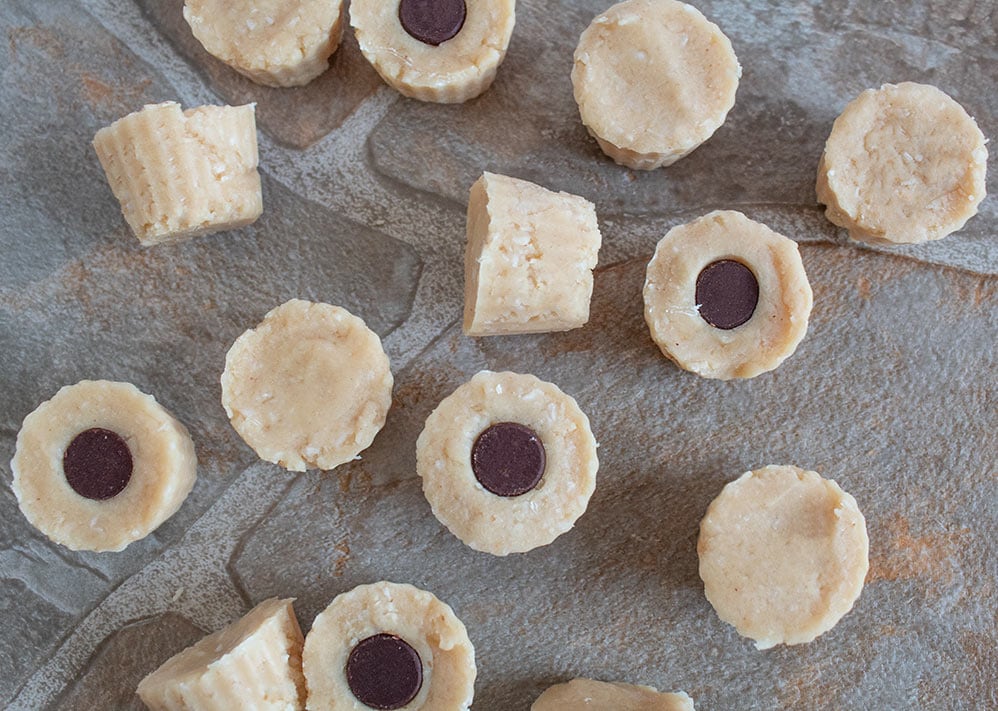 keto peanut butter fat bombs with chocolate chips stuck in some of them on a tile floor