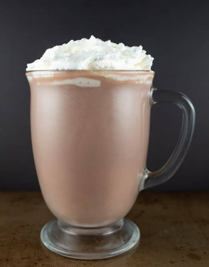 keto hot chocolate against a black background with a ton of whipped cream on top