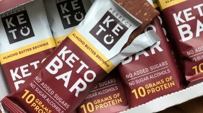 perfect keto bars review in a large box with open bar on top of other bars