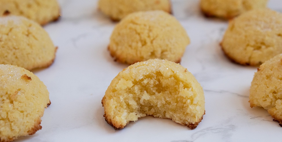 keto macaroon on a white marble countertop with small piece eaten out of middle macaroon