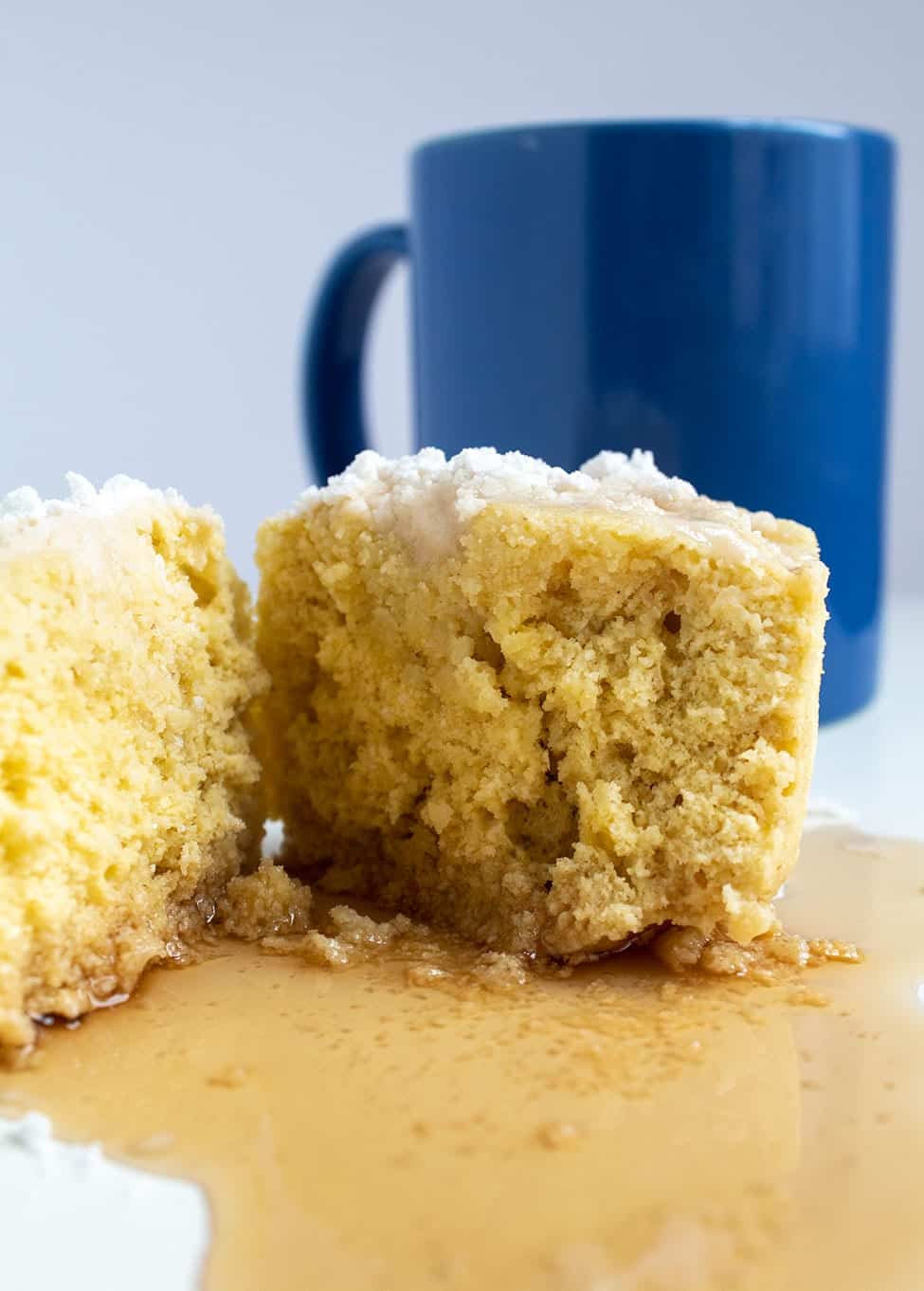 keto pancake mug cake in front of a blue mug with cake split in half