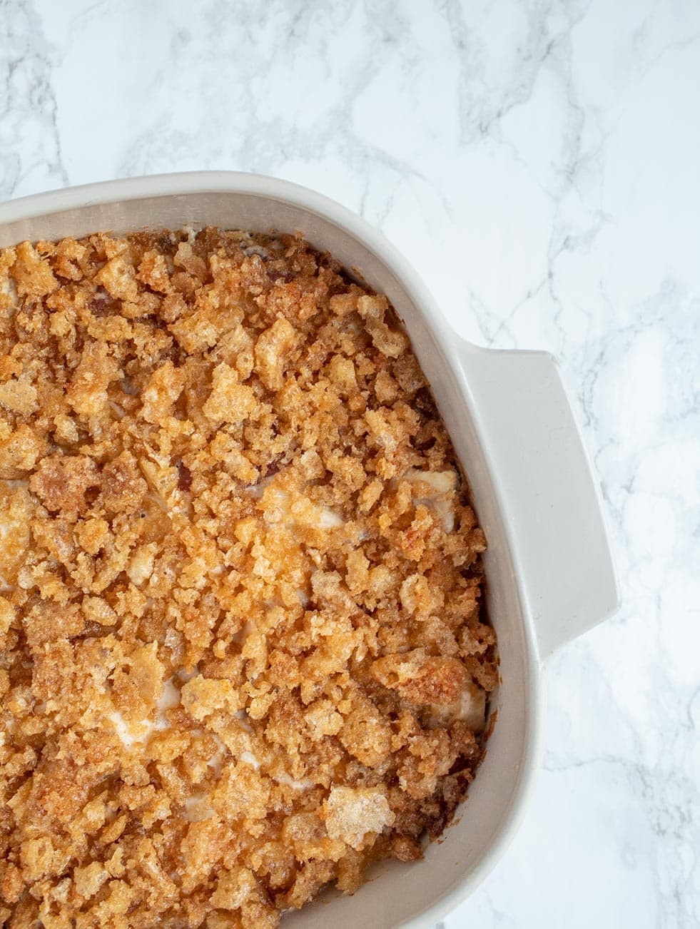 keto casserole with pork rinds crushed on top in a white pan over a marble countertop