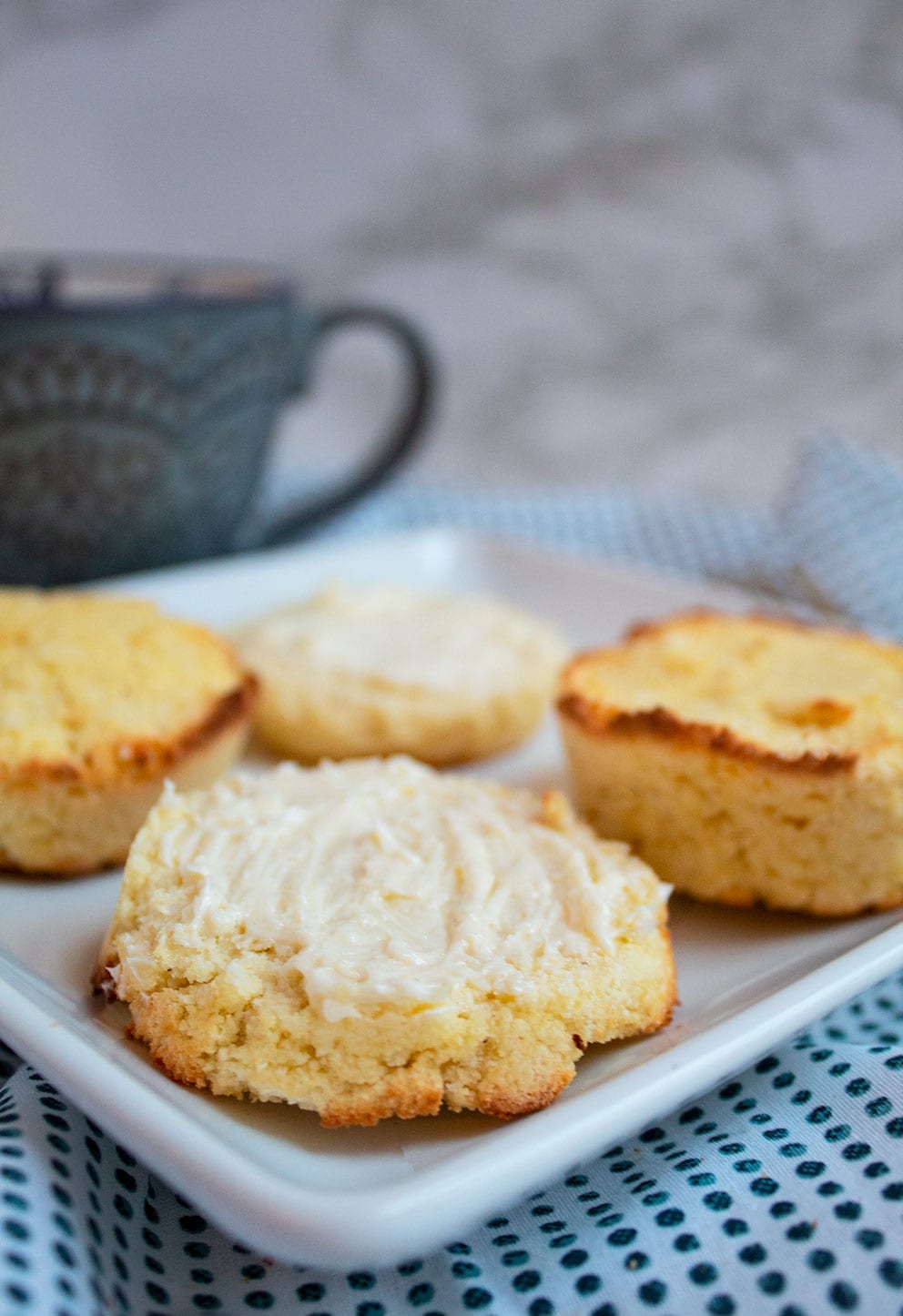 keto cornbread on a white plate cut in half in front of a cup of coffee