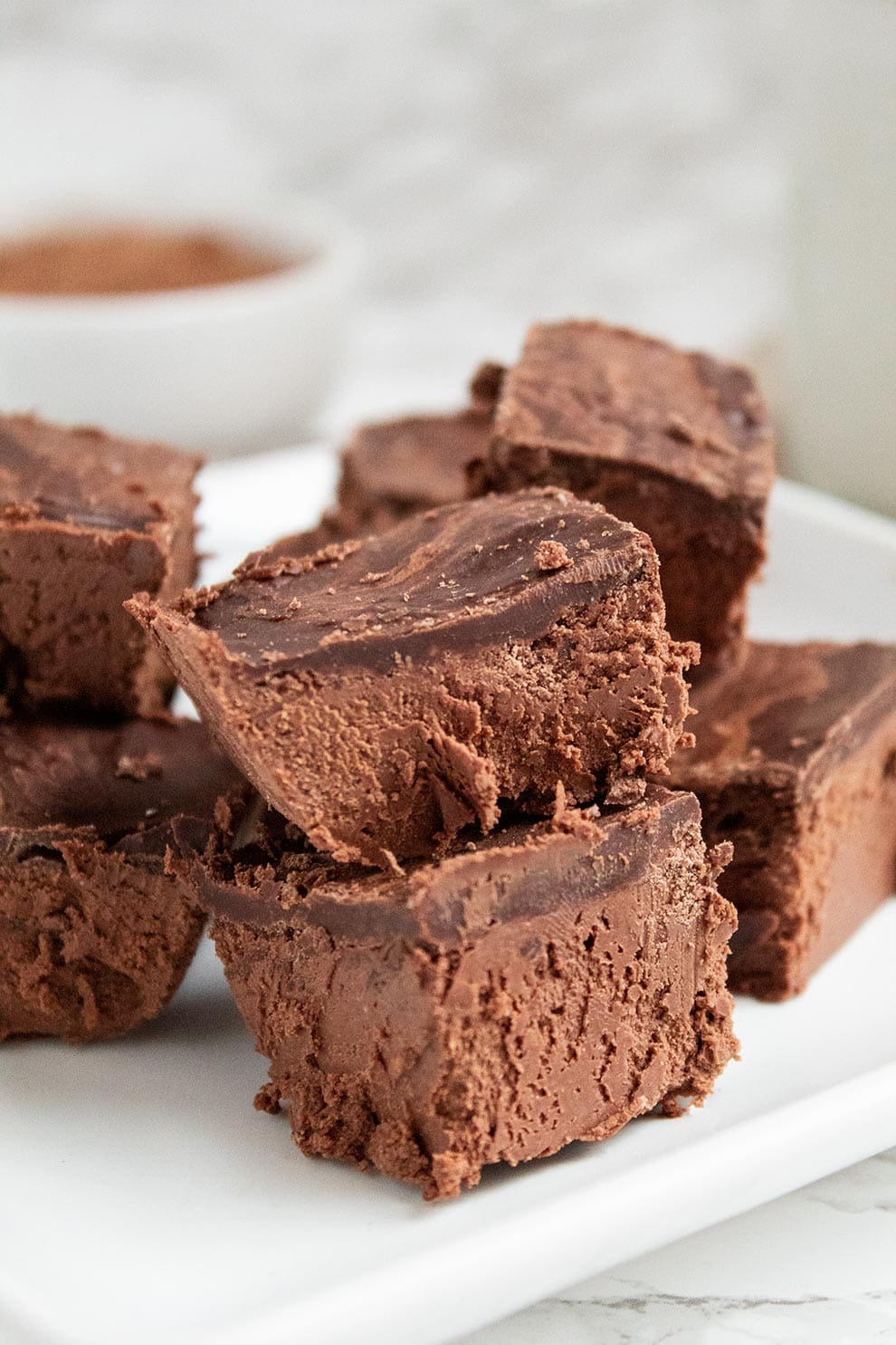 closeup of keto chocolate heaven pieces on a white plate with cocoa powder in the background