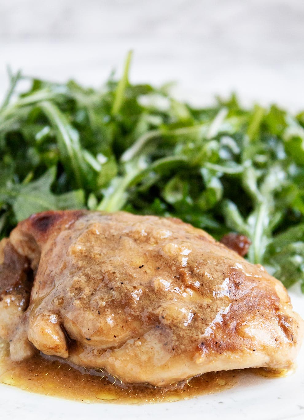 keto chicken thighs in front of a pile of seasoned arugula