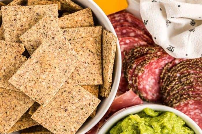keto crackers in a bowl next to meats and cheeses