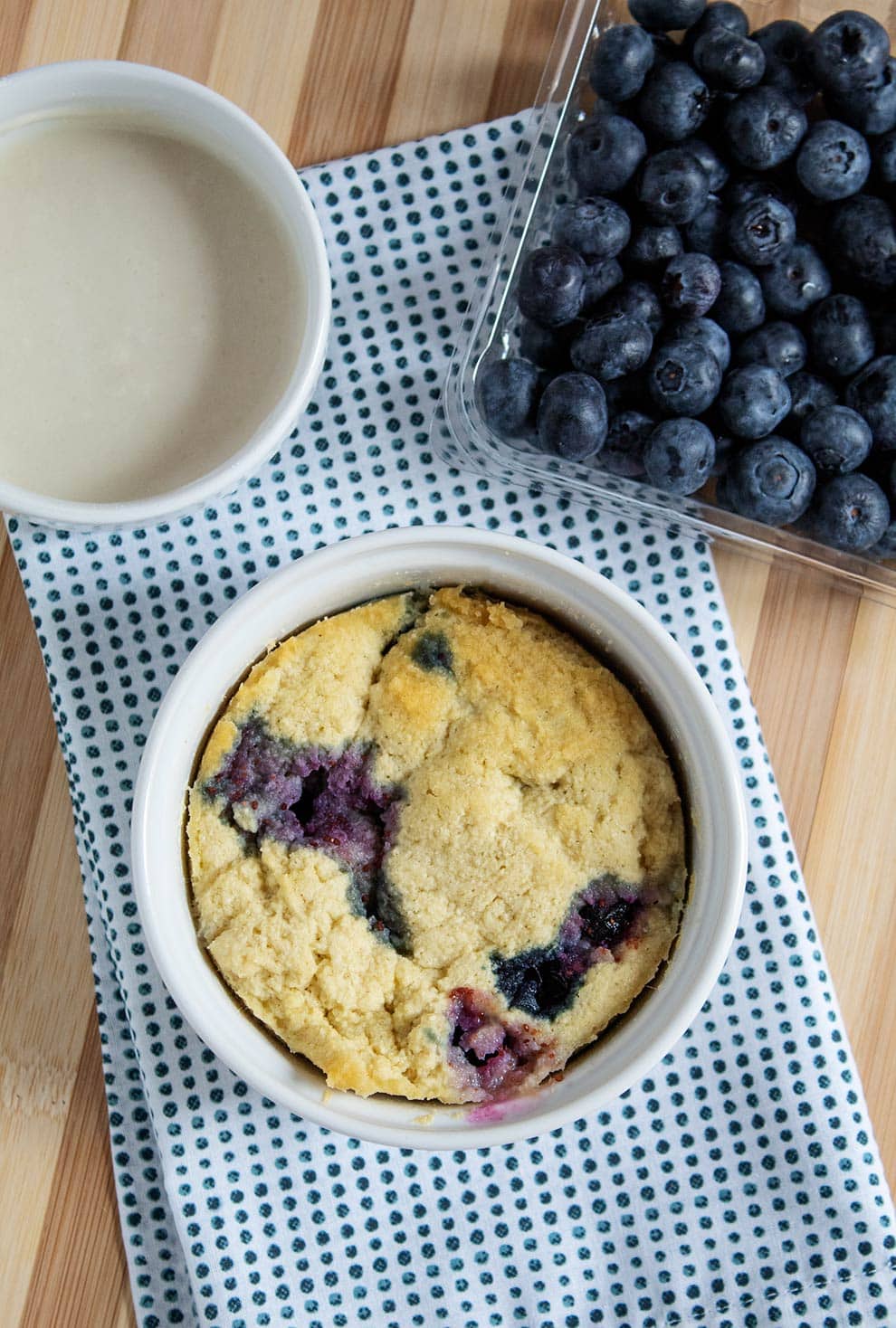 overhead scrutinize of keto blueberry mug cake on a blue and white materials subsequent to blueberries and icing  Keto Blueberry Pancake Mug Cake keto blueberry pancake mug cake 2