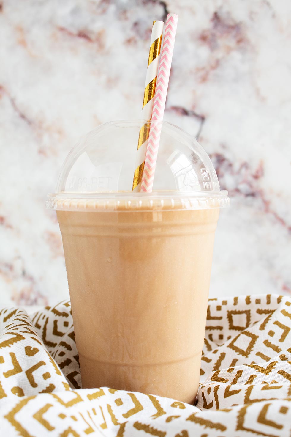 keto frappuccino keto iced coffee in a plastic cup with two decorative straws sticking out