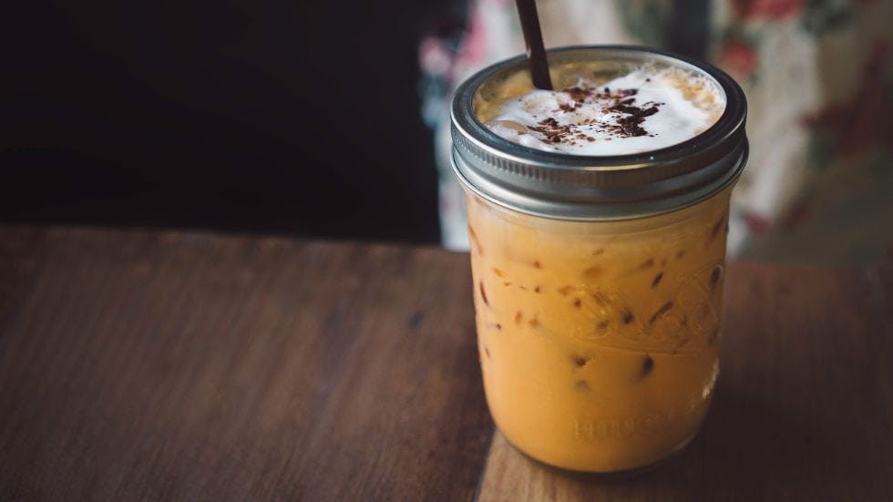 a mason jar of keto iced coffee with whipped cream and cocoa powder on top