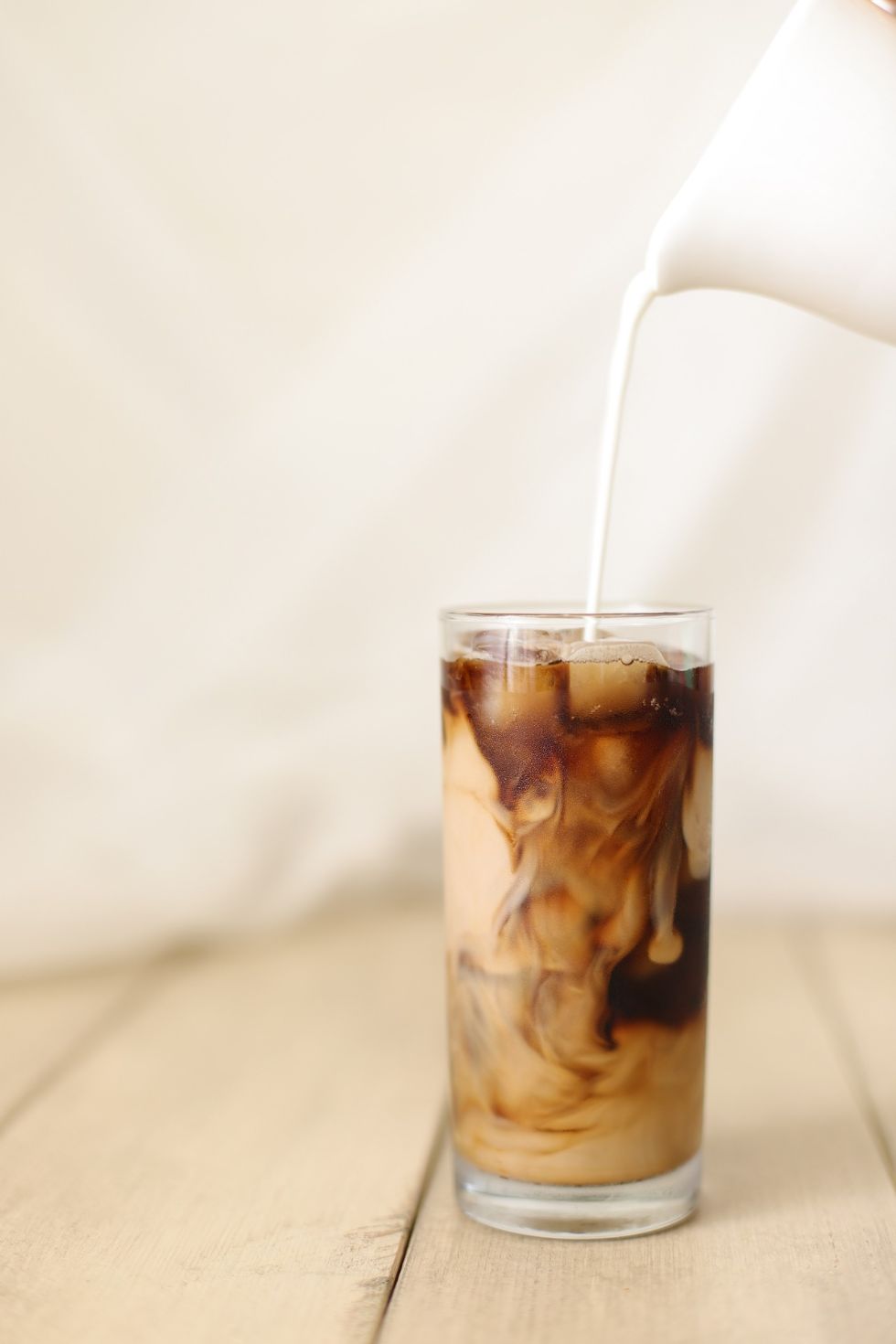 creamer being poured into a mason jar with keto iced coffee inside