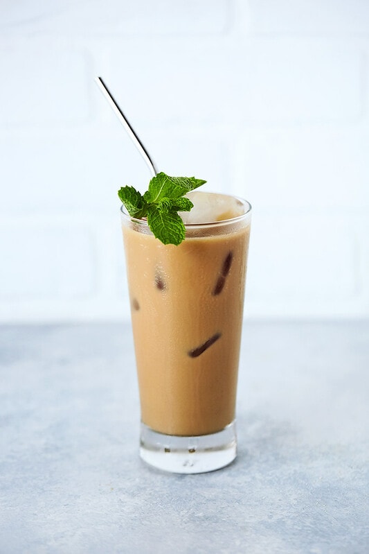 keto iced coffee in a tall glass with mint leaves and a straw sticking out