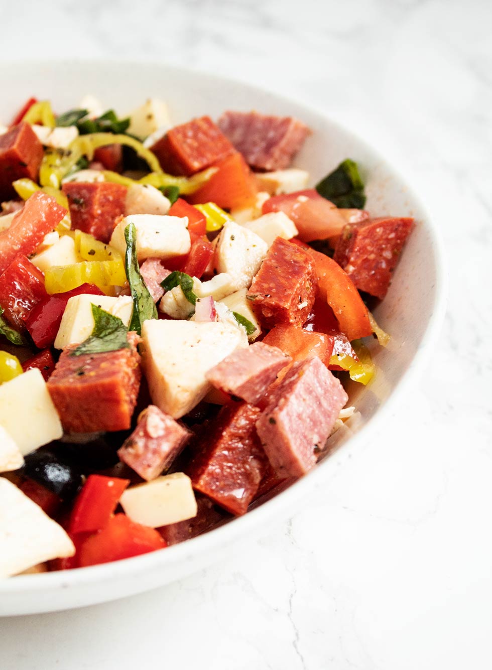 side view of a bowl containing keto antipasto with dressing