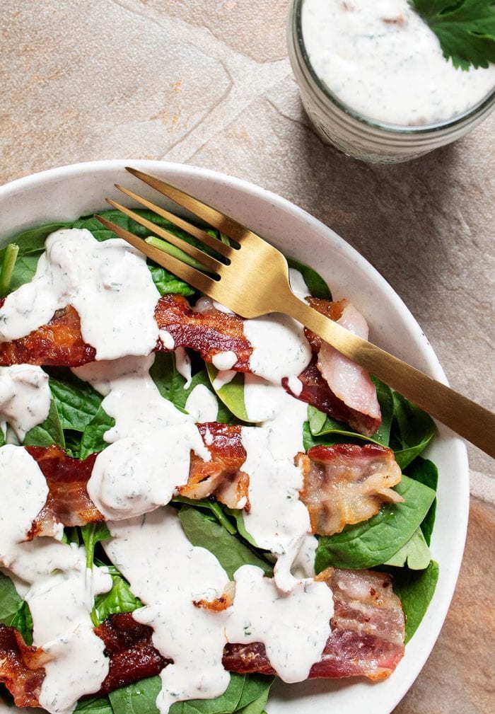 overhead view of large salad with lots of keto ranch dressing and strips of bacon