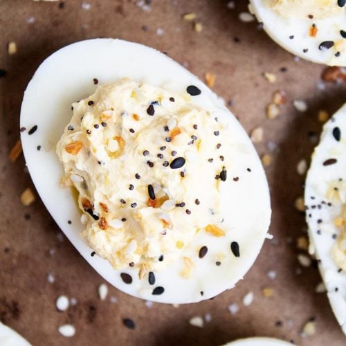 closeup of keto deviled egg on a brown baking sheet surrounded by other keto deviled eggs