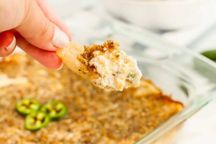 woman's hand scooping keto jalapeno popper dip in pork rind