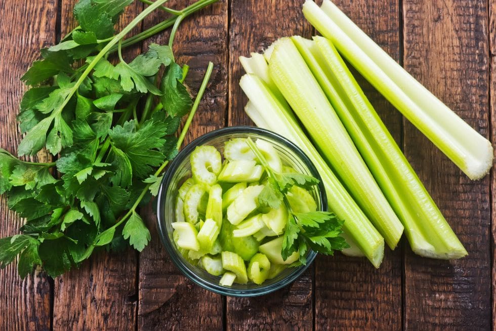 vacker visning av crunchy keto snacks färsk selleri på en skärbräda bredvid en skål med skuren selleri