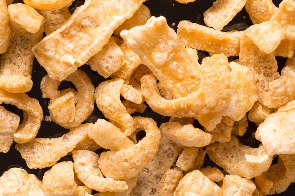 closeup of crunchy keto snacks pork rinds on a black background