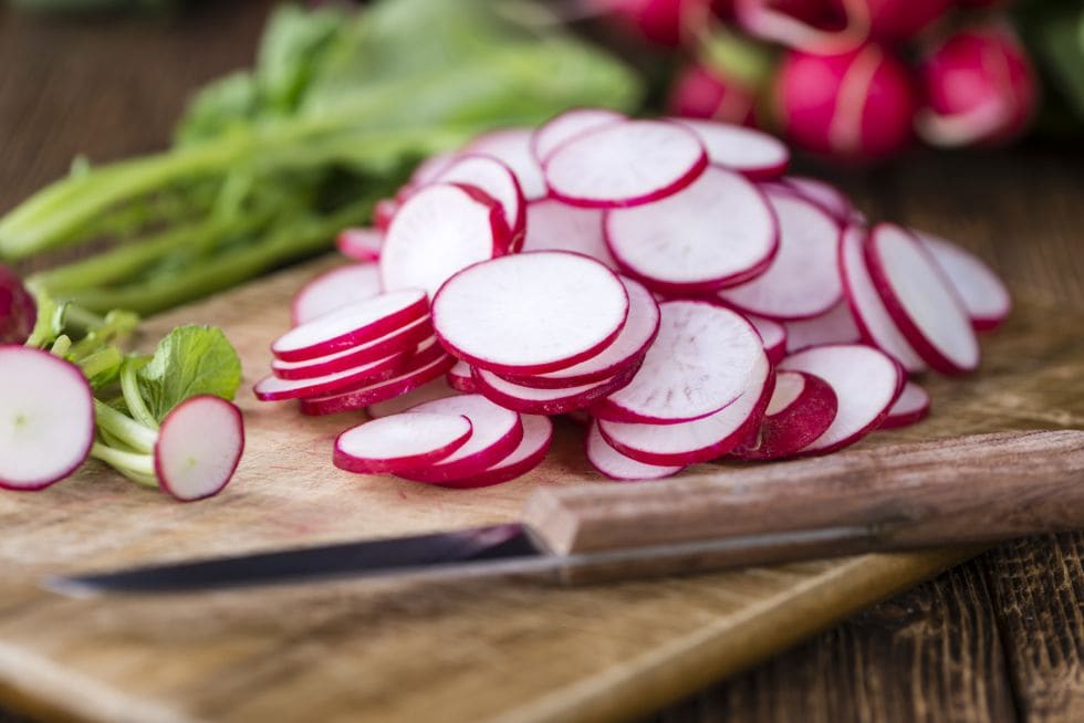 crunchy keto snacks med reddiker skåret opp på et skjærebrett ved siden av en kife