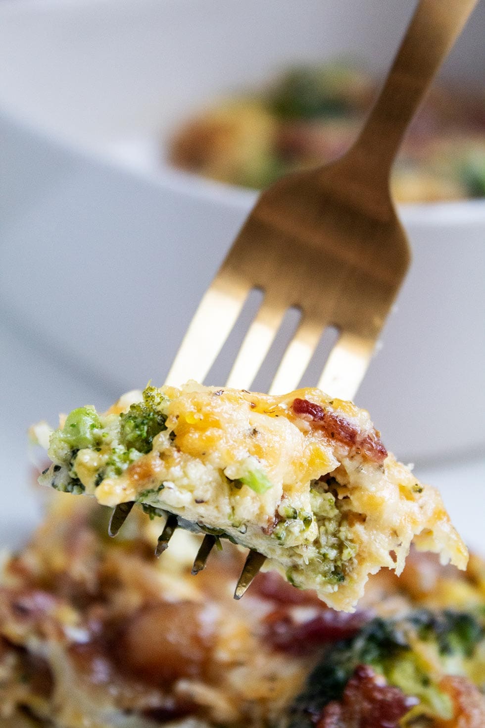 closeup of keto breakfast casserole on golden fork in front of casserole dish