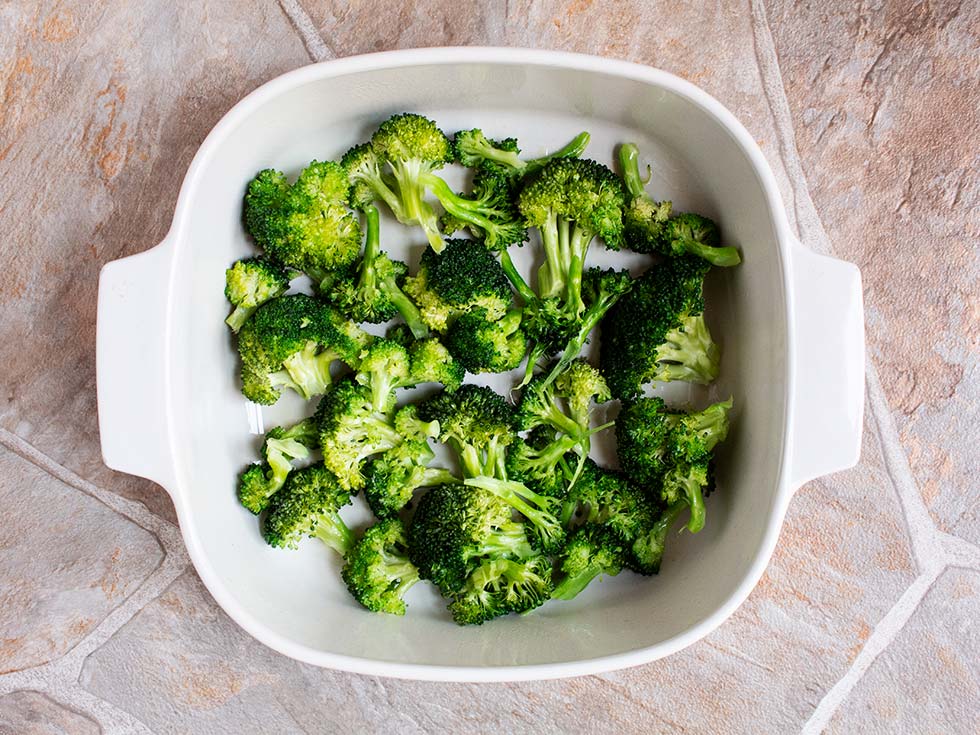 overhead view of fresh steamed broccoli in a white square casserole dish