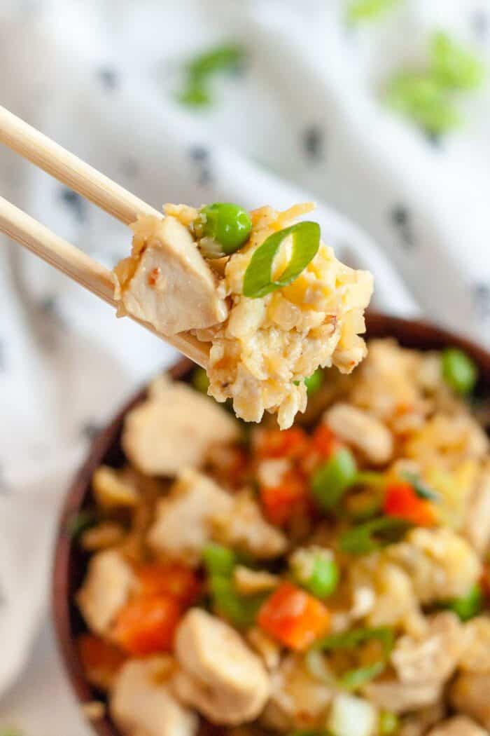 chopsticks holding low carb chicken and rice over top a large bowl