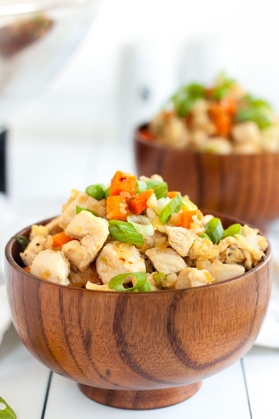 two bowls containing keto chicken fried rice mounded on top on a white background