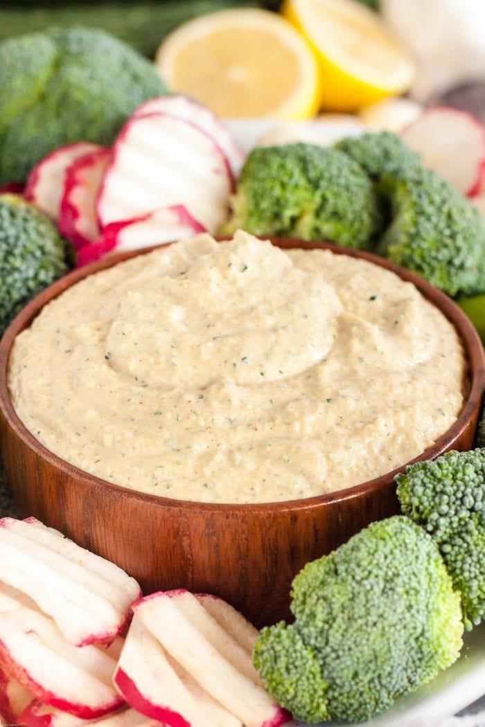 bowl of keto hummus nestled in a bed of fresh radishes and broccoli