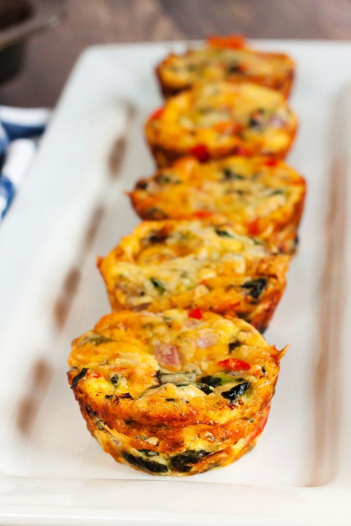 five keto mini quiches lined up on a white decorative plate