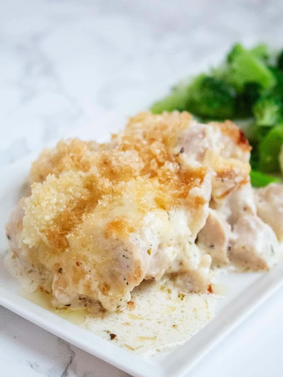 keto alfredo casserole served next to a large pile of bright green broccoli